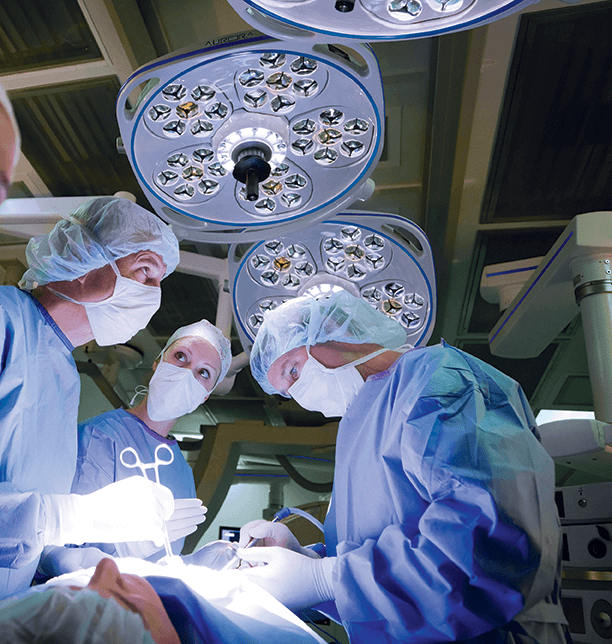 Three surgeons performing a surgery with three Skytron Aurora Four surgical lights